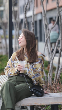 Pensive woman sipping a drink in the streetの写真素材