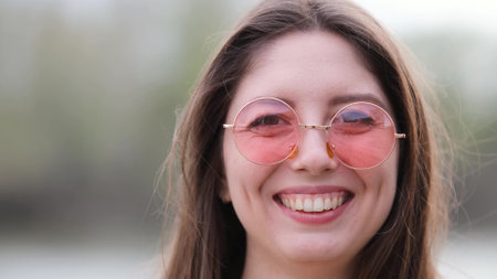 Happy woman in pink sunglasses outdoors smiling