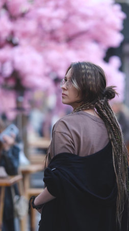 Portrait of a young woman with dreadlocks on a city street. A girl is sitting on the street in the food court area with a glass of coffee in her hand. She is getting ready to meet her friends.の写真素材