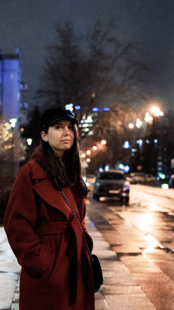Young woman standing on the sidewalk waiting for a taxi. Peaceful atmosphere in the evening on a...