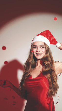 Happy woman with long hair in New Years hat and red dress posing on white background at New Years party style photo shootの写真素材