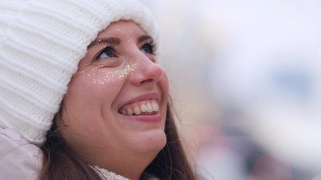 Portrait of a woman in a warm white knitted hat outdoors in winter. Young woman smiling and enjoying...