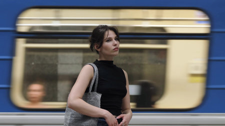 Beautiful brunette stands at the metro station waiting for the train to arrive