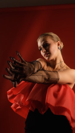 Portrait of photo model posing in red dress and black transparent gloves. Girl on red background.の写真素材