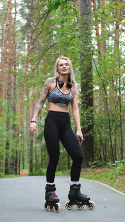 Attractive blonde feels free and light while rollerblading in city park in summer. Stunning...
