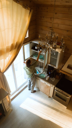 Woman washes glasses under running water, washes dishes in kitchen sinkの写真素材