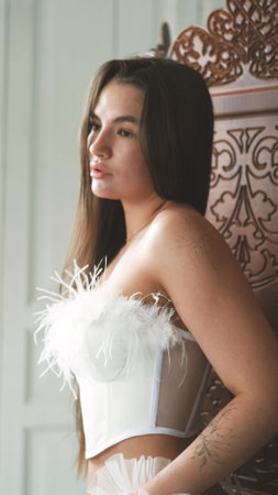 Portrait of young beautiful model posing in white lingerie, corset, gloves and stockings. Calm cute brunette with long hair in fashionable lingerie.の写真素材