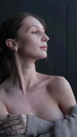 Portrait of a young girl with bare shoulders on a dark studio background. Beautiful natural woman posing for the cameraの写真素材