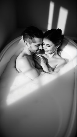 Monochrome image of a bathtub filled with foam. In the bathtub, a woman and a man in love are embracingの素材