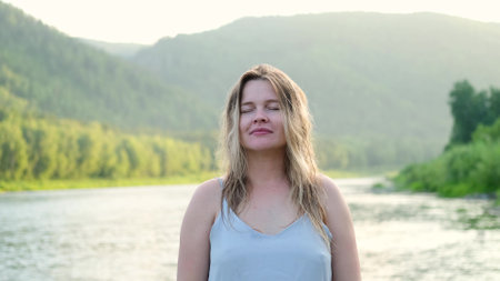 Beautiful young woman relaxing and enjoying the sunset. Portrait of a girl against the backdrop of summer nature. Pretty happy lady enjoying summer outdoors. Positive emotions, life success, peace concept.の写真素材