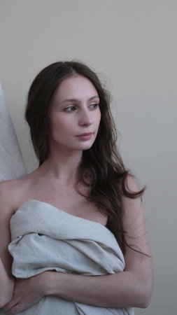Portrait of a beautiful brunette with long hair on a fabric background in the studio. Beautiful natural woman posing for the cameraの写真素材