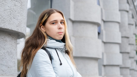 Portrait of sad, thoughtful young woman in blue jacket outdoors