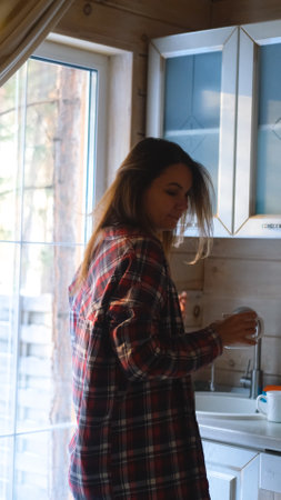 Young woman enjoying her favorite music, dancing in the kitchen in the morning and drinking coffee.の写真素材