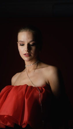 Portrait of photo model posing in red dress and black transparent gloves. Girl on red background.の写真素材