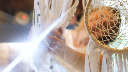 Woman making dreamcatcher from threads, feathers, beads and silk ribbons, making home decor items, handmade amuletの写真素材