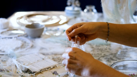 Woman making dreamcatcher from threads, feathers, beads and silk ribbons, making home decor items, handmade amuletの写真素材