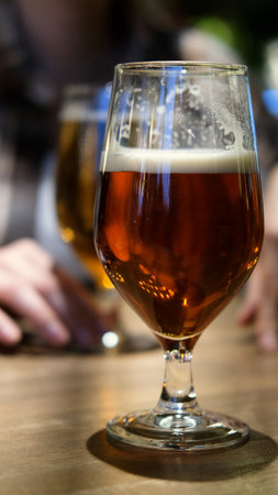 The concept of meeting friends in a bar. Close-up of two glasses of beer on a table, blurred backgroundの写真素材
