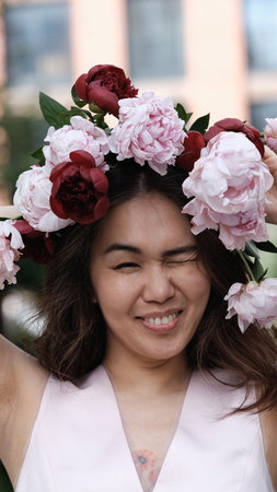 Portrait of a beautiful smiling woman with a wreath of peonies on her head. Natural beauty concept.の写真素材
