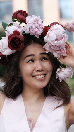 Portrait of a beautiful smiling woman with a wreath of peonies on her head. Natural beauty concept.の写真素材