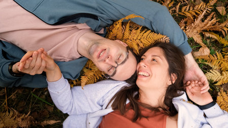 A woman and a man in love lie in tall yellow grass, in fern leaves. The married couple relaxes in...