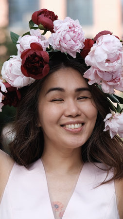 Portrait of a beautiful smiling woman with a wreath of peonies on her head. Natural beauty concept.の写真素材