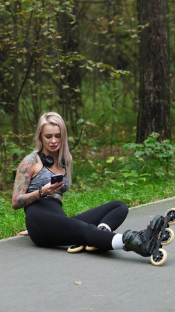 Attractive blonde relaxes while roller skating. She sits on the bike path and poses for the camera....