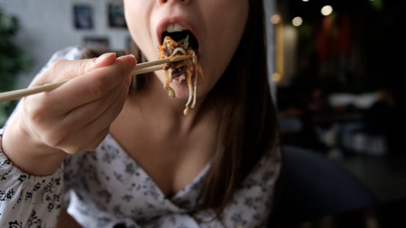 Close-up of Caucasian woman eating pan-Asian cuisineの写真素材