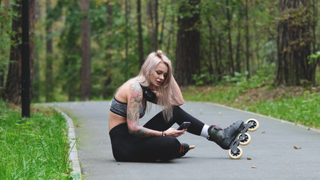 Attractive blonde relaxes while roller skating. She sits on the bike path and poses for the camera....