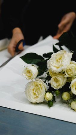 Beautiful white roses in a flower shop. Florist assembles a bouquet to orderの写真素材
