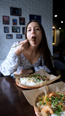 Close-up of Caucasian woman eating pan-Asian cuisineの写真素材