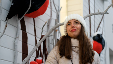 Portrait of a beautiful young woman in winter clothes. The woman smiles happily against the backdrop...