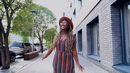 Young woman resting and relaxing while walking on city street in new eco-friendly residential...