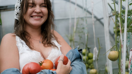 A girl collects organic tomatoes in a greenhouse in the village, is engaged in farming.の写真素材