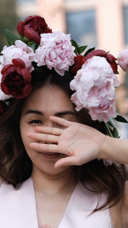 Portrait of a beautiful smiling woman with a wreath of peonies on her head. Natural beauty concept.の写真素材