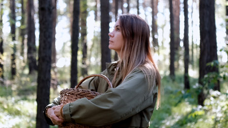 Portrait of a woman breathing fresh air in an autumn forest. The woman enjoys a walk in the forest and a beautiful warm dayの写真素材