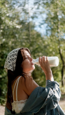 Portrait of a beautiful young woman in the countryside. The woman holds a bottle of milk in her hands.の写真素材