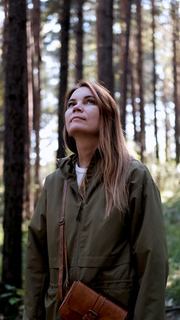 Portrait of a woman breathing fresh air in an autumn forest. The woman enjoys a walk in the forest and a beautiful warm dayの写真素材