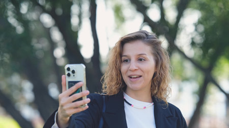 Woman with curly hair talking on smartphone on the street. Close-up. Communication technologies and modern lifestyle concept.の写真素材