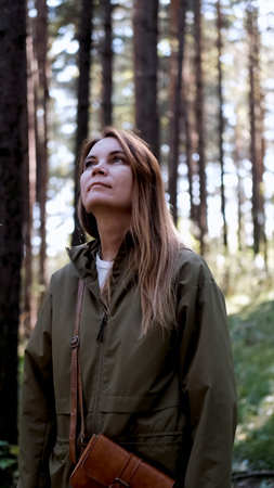 Portrait of a woman breathing fresh air in an autumn forest. The woman enjoys a walk in the forest and a beautiful warm dayの写真素材