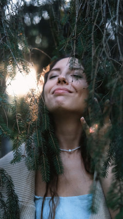 Portrait of a young woman in a summer spruce forest at sunset.の写真素材