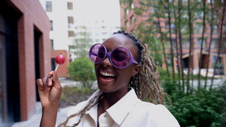 A woman poses for a smartphone selfie, holding a sweet lollipop.の写真素材
