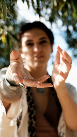A beautiful brunette dressed in boho style meditates and dances in the forest. A ritual takes place against a green forest backdrop.の写真素材