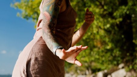A beautiful brunette dressed in boho style meditates and dances in the forest. A magical ritual takes place against a green forest backdrop.の写真素材