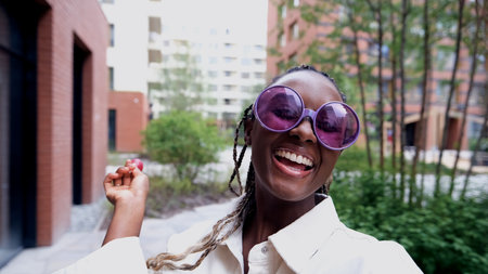 A beautiful woman poses for a smartphone selfie, holding a sweet lollipop.の写真素材
