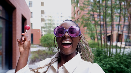 A woman poses for a smartphone selfie, holding a sweet lollipop.の写真素材