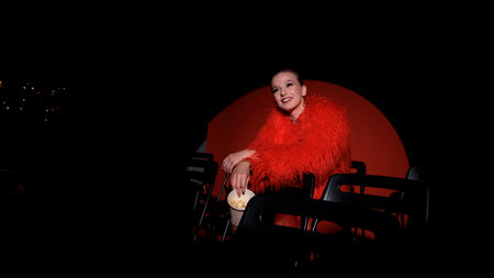 Portrait of a beautiful young woman in a red fur coat against a red background, posing for a...
