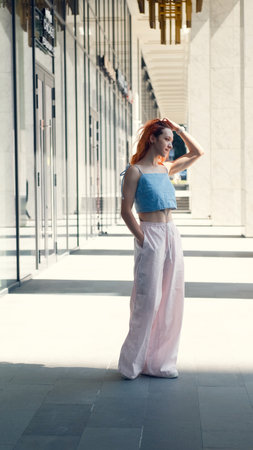 A portrait of a teenage girl with red hair posing for a photo near columns at the entrance to a business centerの写真素材