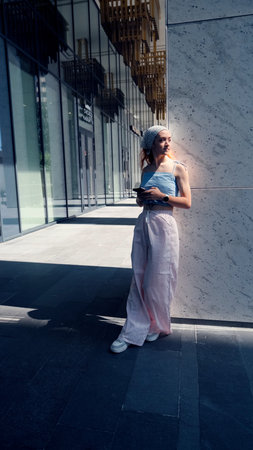 A portrait of a teenage girl with red hair posing for a photo near columns at the entrance to a business centerの写真素材