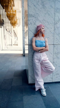 A portrait of a teenage girl with red hair posing for a photo near columns at the entrance to a business centerの写真素材