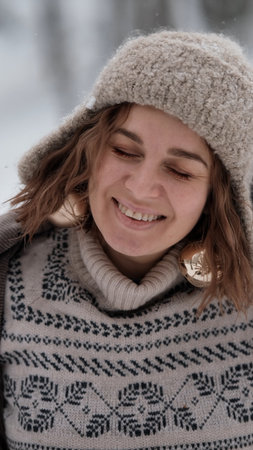 A beautiful woman in winter clothing enjoys her free time in a snowy forest. Portrait of a woman enjoying the first snow. Active winter recreation.の写真素材